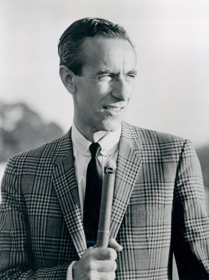 1964 archive publicity portrait of broadcaster Chris Schenkel holding an ABC microphone.